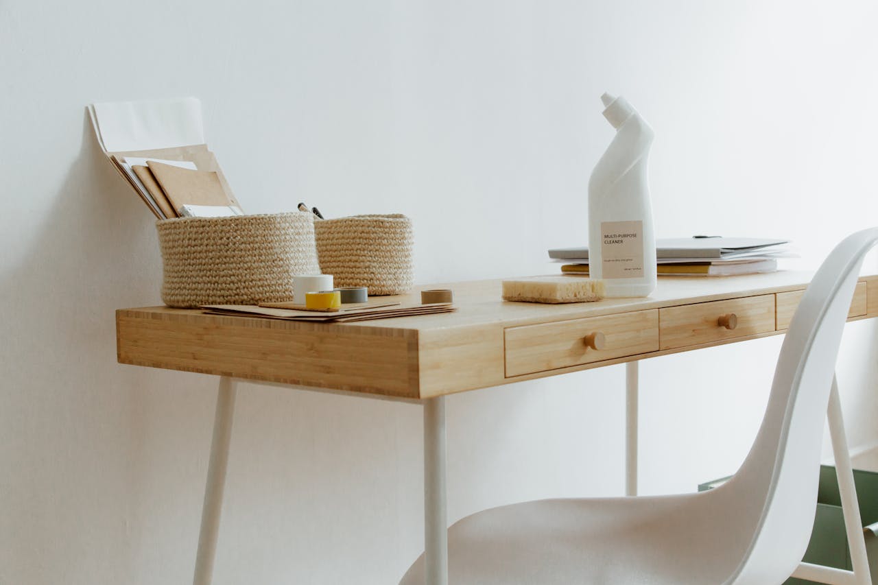 hero-img A clean and organized home office desk with cleaning products, papers, and storage baskets.